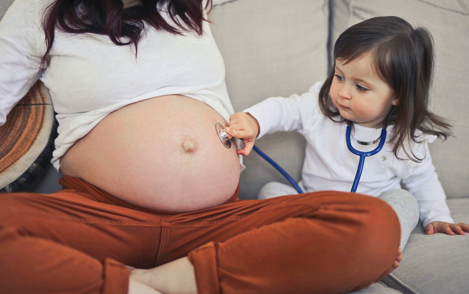 little girl listens with a stethoscope in the belly of pregnant mom1500