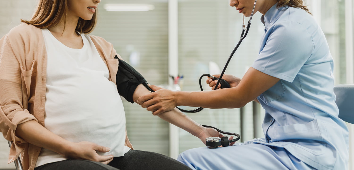 gynecology nurse talking pregnant woman checking blood pressure her1500